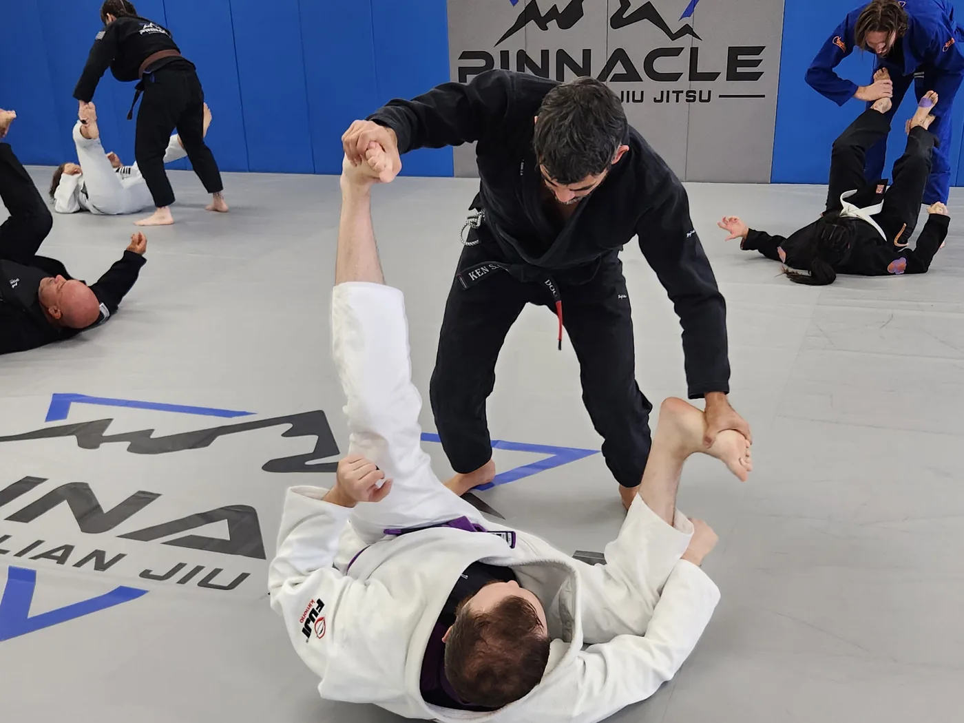 Adult students drilling with a coach during an all-levels class at Pinnacle Brazilian Jiu Jitsu