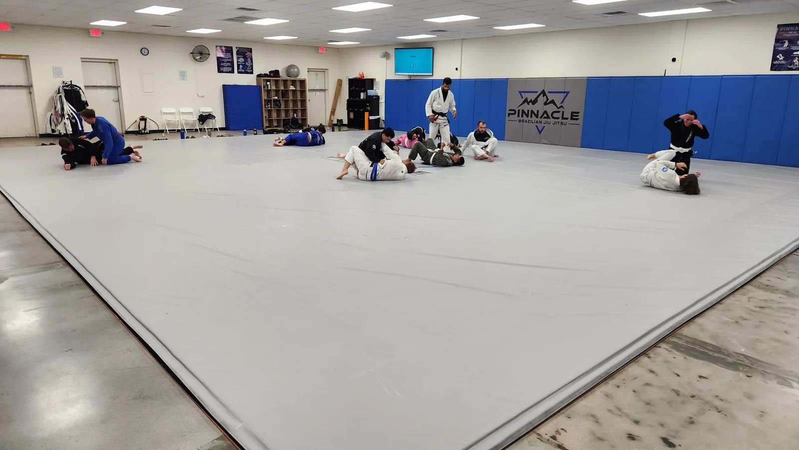 A wide view of the training floor at Pinnacle Brazilian Jiu Jitsu with the class rolling