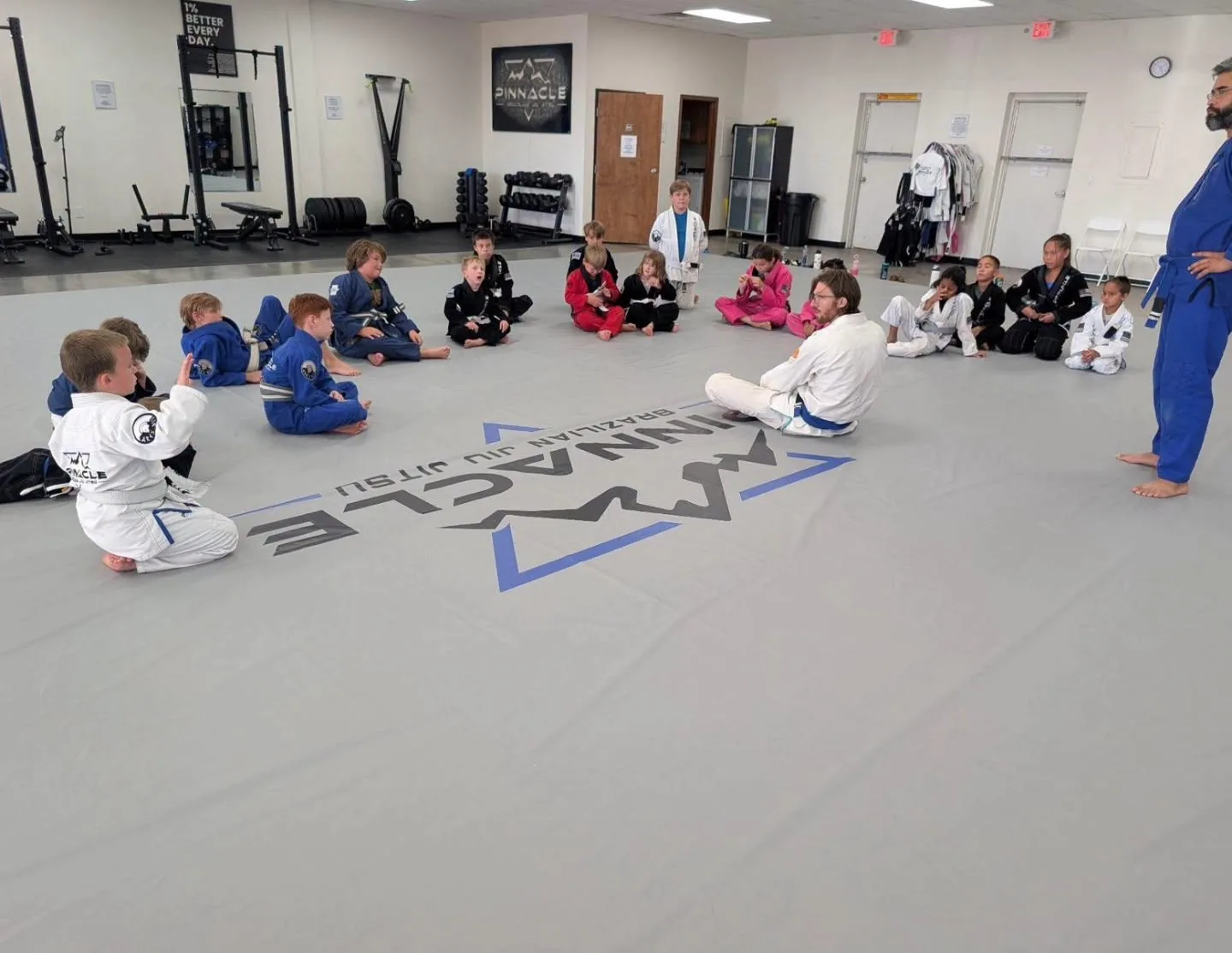 Kids BJJ class sitting on the mats listening to their coaches at Pinnacle