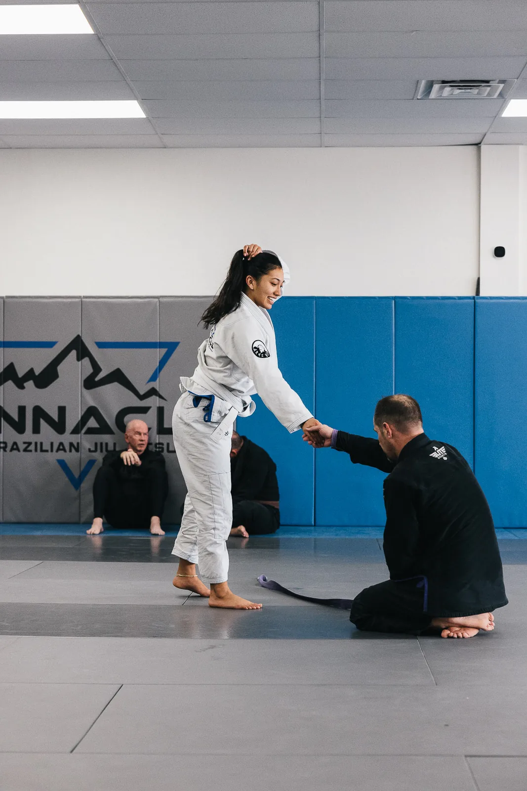 A student being congratulated by her coach on the mats at Pinnacle